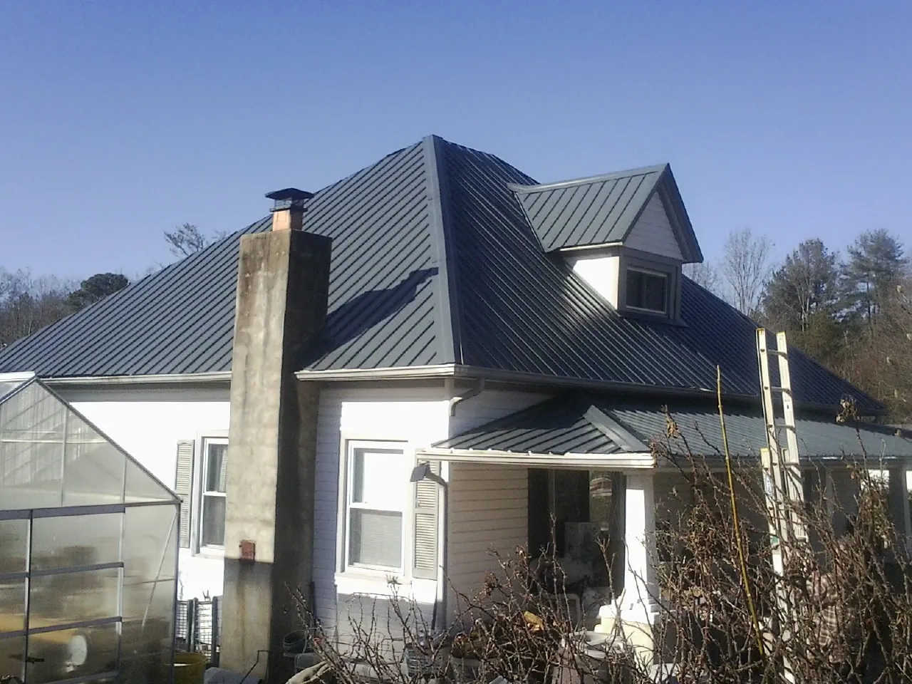 Dark blue standing seam metal roof on a white farmhouse with dormer — Slate & Tile Roof Repair by Roofing Brothers in Norwood Young America