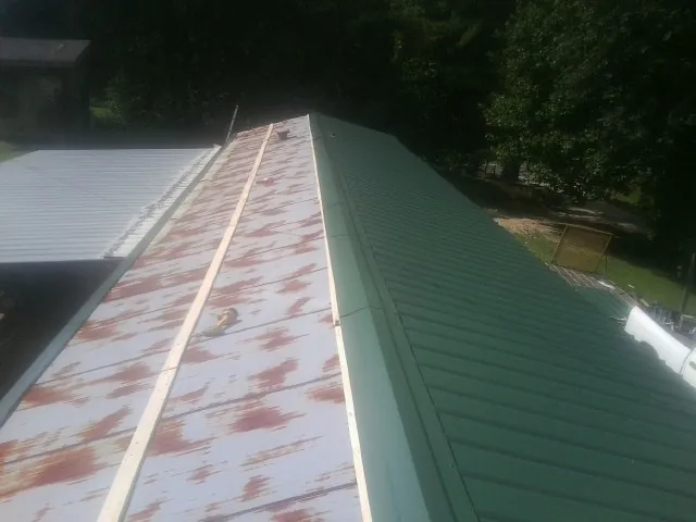 Old rusted panels beside newly installed green metal roofing — Wind Damage Roof Repair by Roofing Brothers in Norwood Young America