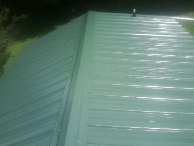 New green metal panels meeting at the ridge of a roof — Flat Roof Repair work by our crew in Norwood Young America