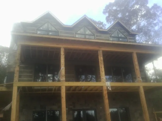 Dormers and porch framing on a large log home under construction — Roof Coating work by our crew in Norwood Young America