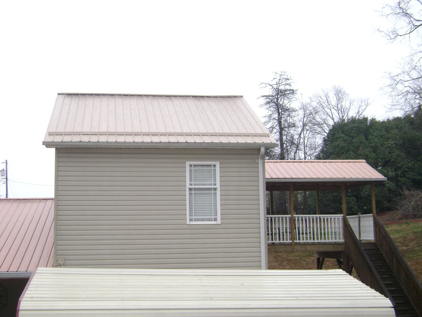 Tan metal roofs on a two story addition and attached porch, from a Roof Replacement job in Norwood Young America