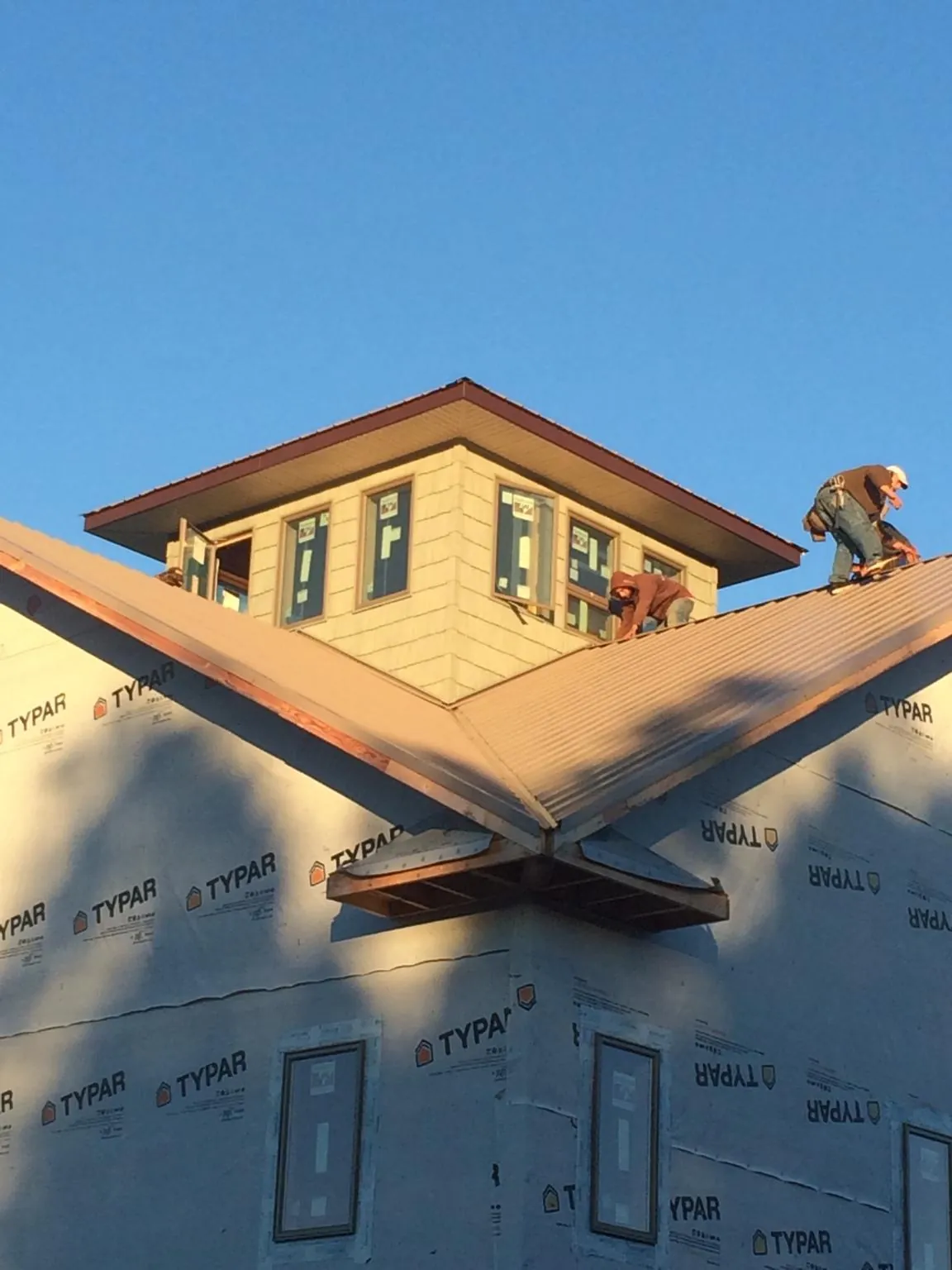 Roofers working around a rooftop cupola on a new metal roof at sunset — Roof Waterproofing in Norwood Young America by Roofing Brothers
